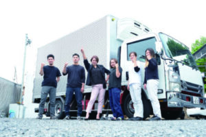 「地元密着でやっていきたい」という尾﨑社長（左から３人目）と従業員ら。遠方や大きなトラックでの運搬は男性ドライバーが担う
