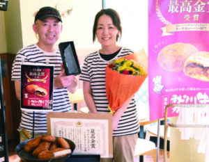 カレーパンを前に受賞を喜ぶ店主の野田さんと妻の久恵さん。手にする花束は受賞祝いに常連客から贈られたもの