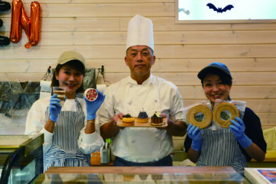 期間限定のハロウィーンケーキを手に小野田シェフ（中央）と従業員ら